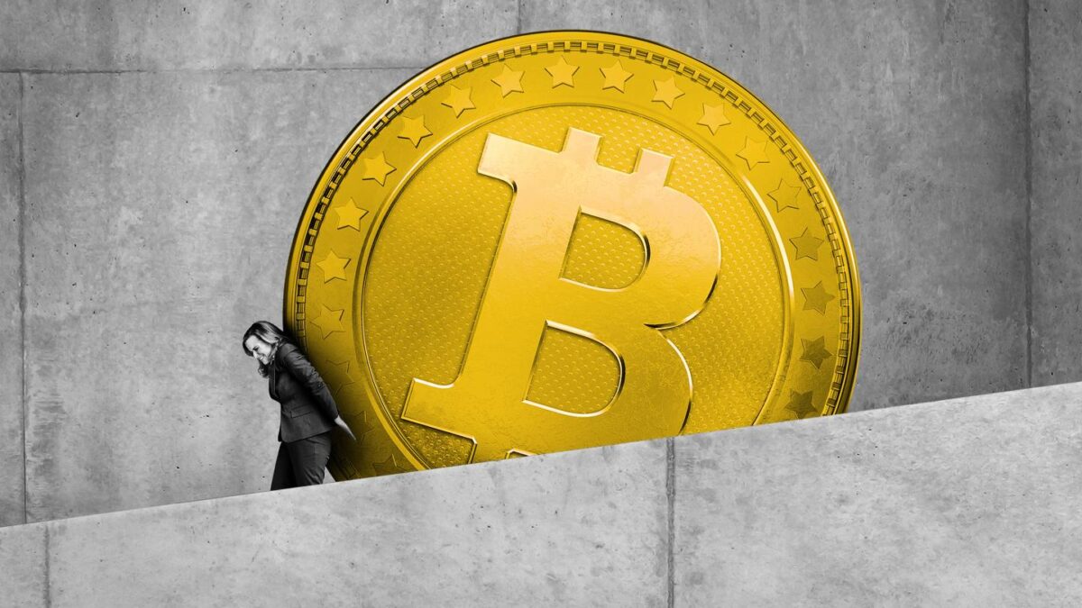 A businesswoman attempts to push Bitcoin up a sloped ramp.