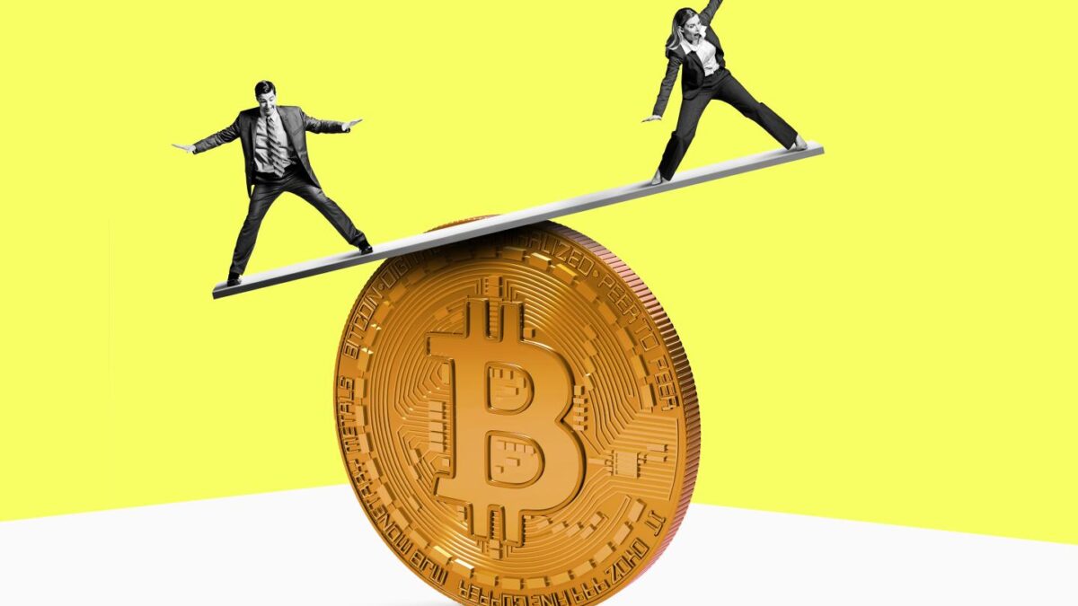 Two people balance on top of a Bitcoin.