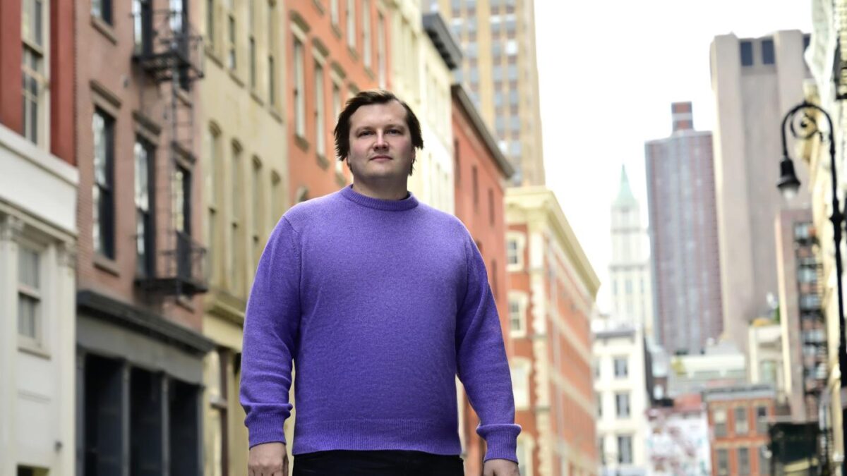 Stani Kulechov stands in NYC with backdrop of buildings.