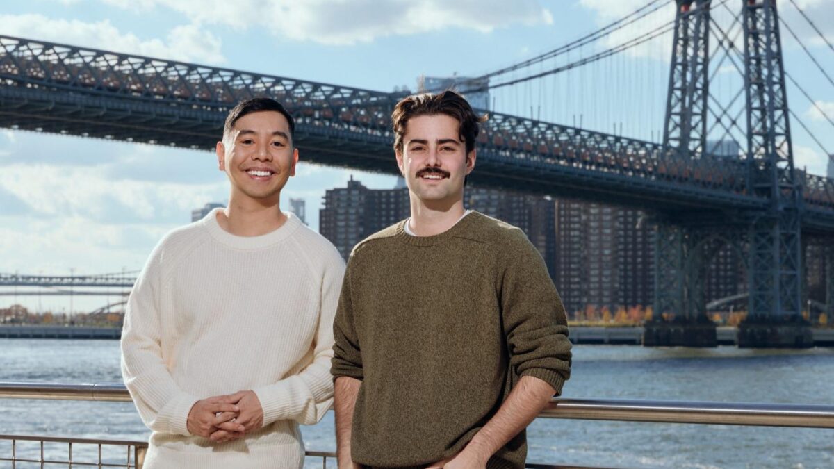 Two men stand in front of the Manhattan Bridge