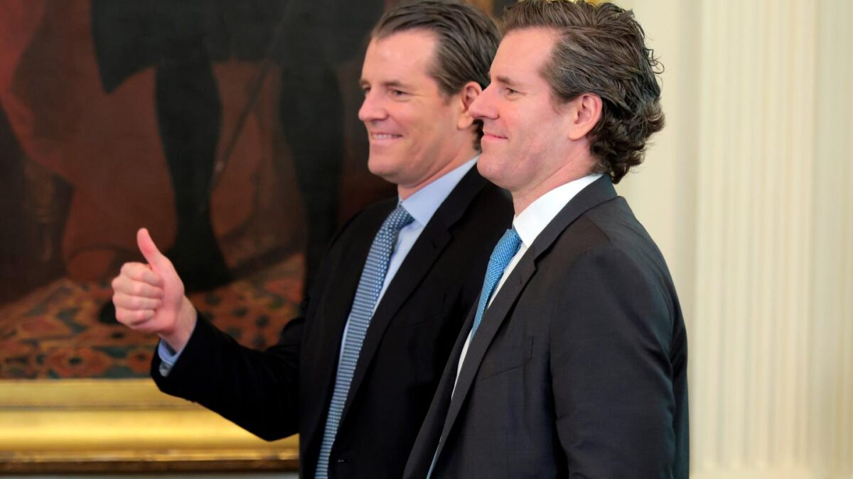 Two men in suits smile in front of a painting