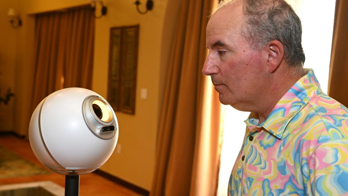 Wedbush Securities analyst Dan Ives stares into an orb, a device that scans human eyeballs and gives them Worldcoin in return.