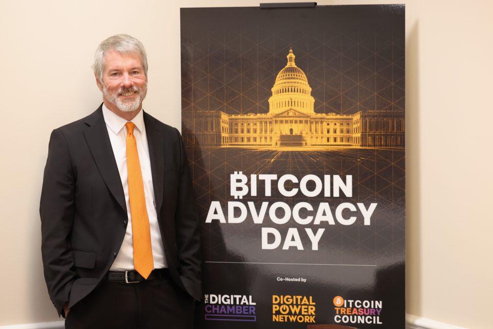 gettyimages-2235778540-e1763381995977 Michael Saylor next to a poster that says "Bitcoin Advocacy Day."