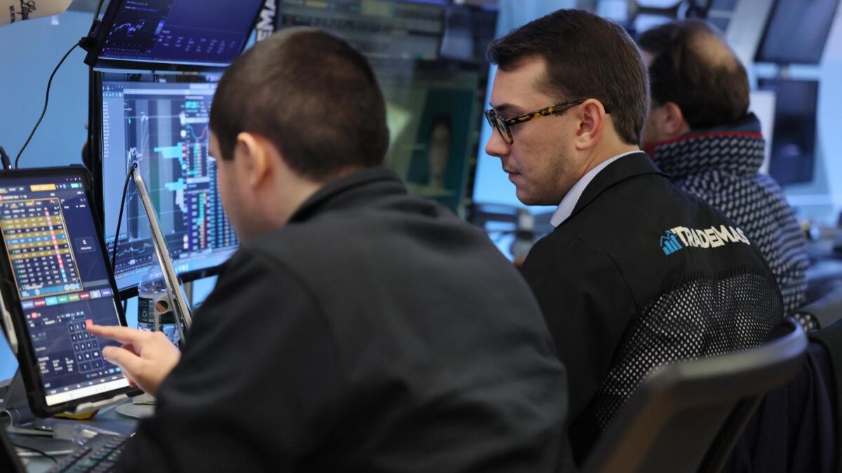 Two men are looking at monitors while trading