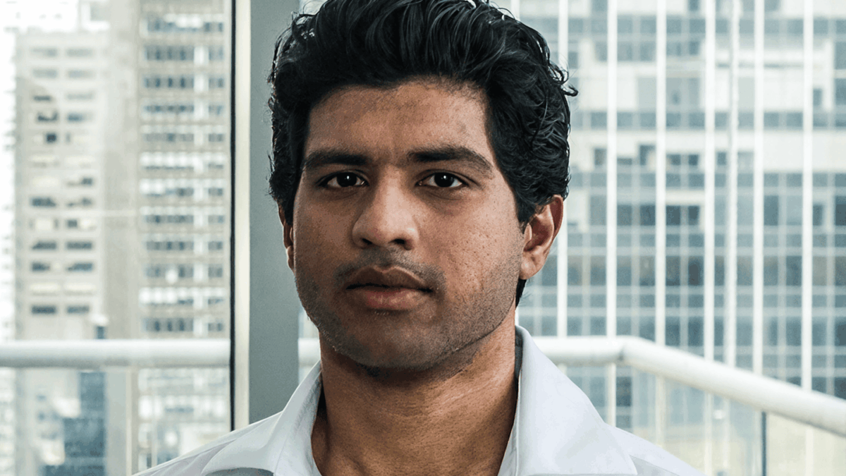Abhi Pingle looks into the camera in front of an office window.