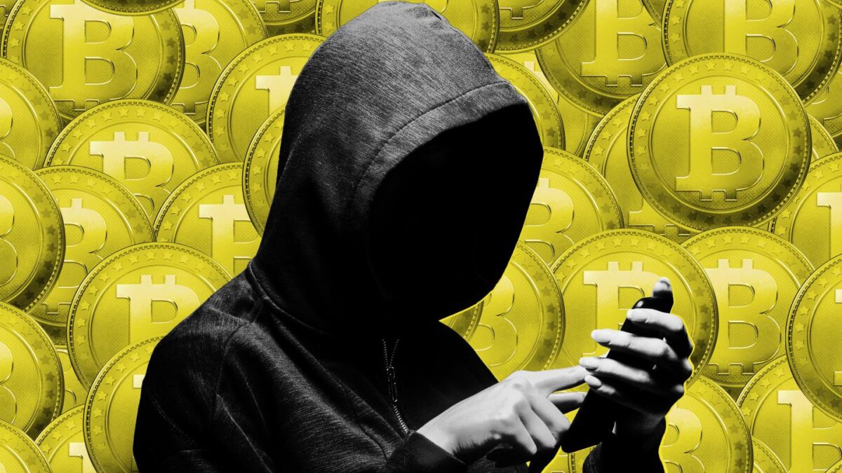 Hooded hacker stealing information with a phone.