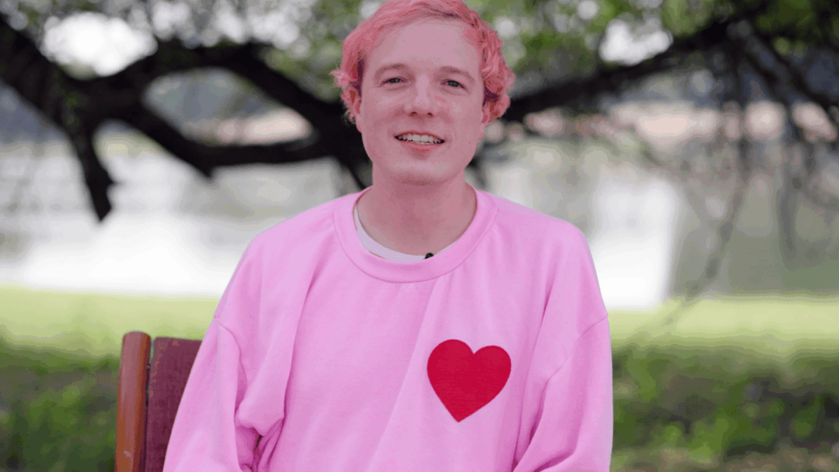 CEO and cofounder David Vorick sits in front of a tree wearing a pink sweatshirt with a red heart on it