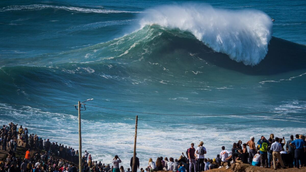 Photo: NAZARE, PORTUGAL - 2020/10/29: Despite the COVID-19 pandemic alert to social withdrawal, thousands of people attended the first big swell of the winter season in Praia do Norte. (Photo by Henrique Casinhas/SOPA Images/LightRocket via Getty Images)