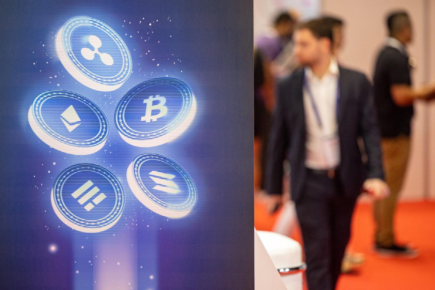 A man walks juxtaposed to a graphic of various cryptocurrencies.