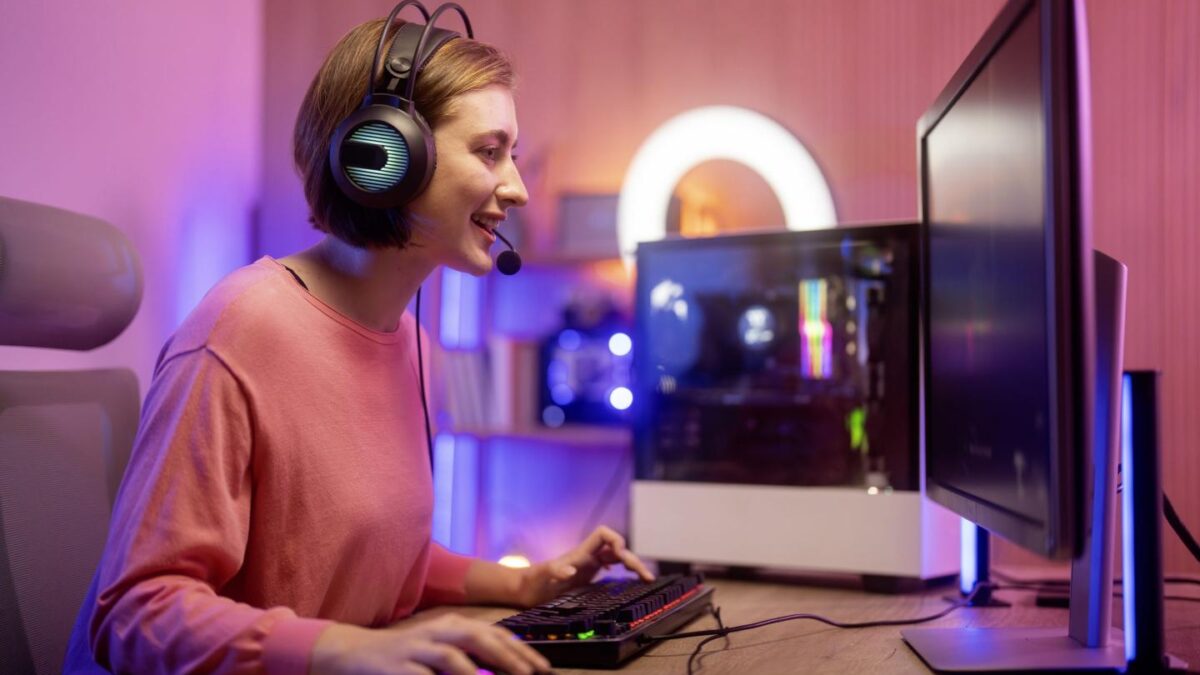 Female gamer sits in front of gaming monitor with headphones on