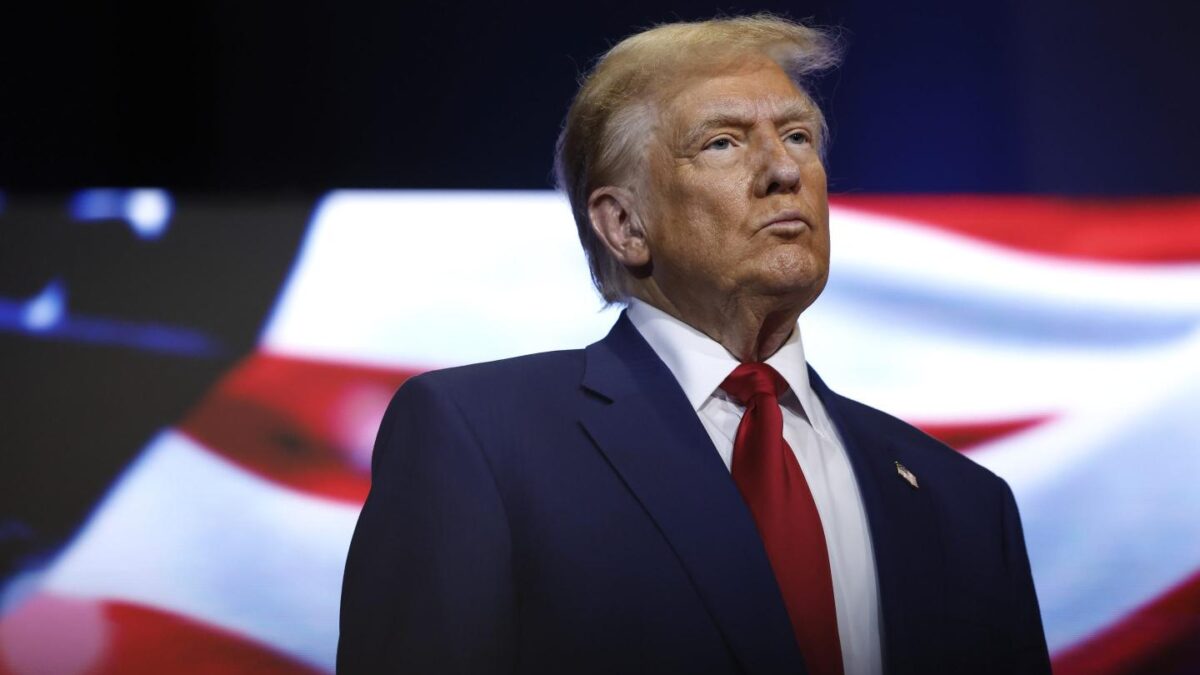 Donald Trump stands in front of an American flag at a roundtable with faith leaders in Georgia.