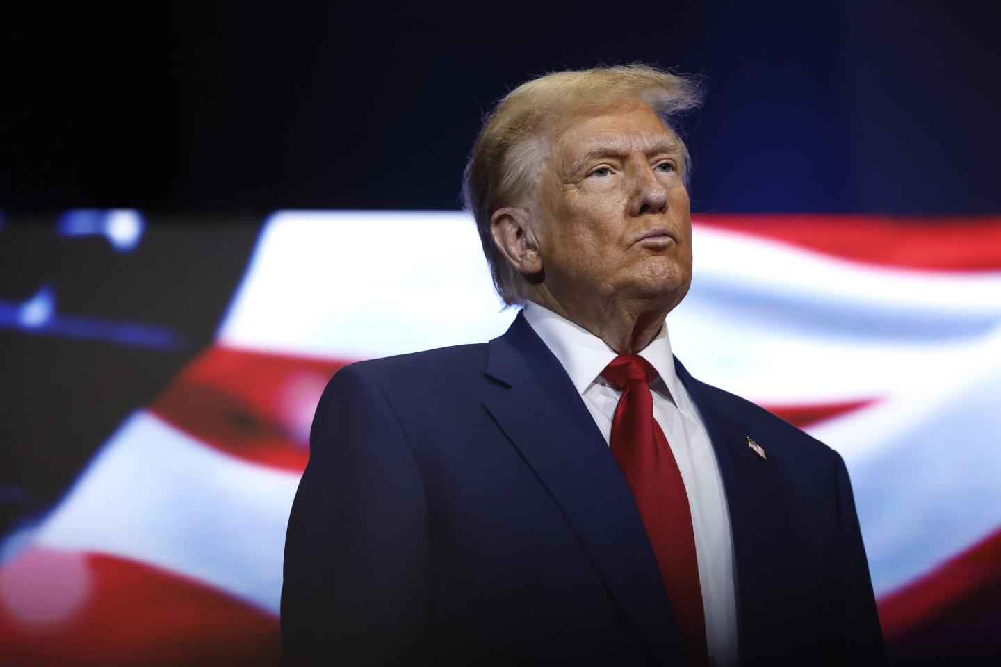 Donald Trump stands in front of an American flag at a roundtable with faith leaders in Georgia.